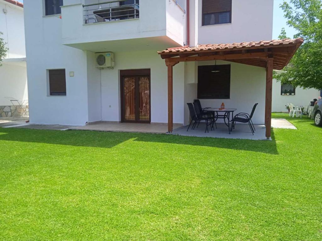 a patio with a table and chairs in a yard at Mary's House in Vourvourou