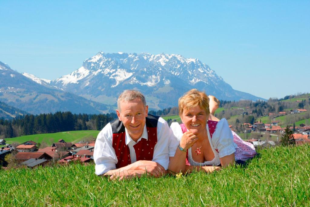 zwei Menschen im Gras mit einem Berg im Hintergrund in der Unterkunft Ferienwohnungen Fam Michael Neumaier in Reit im Winkl