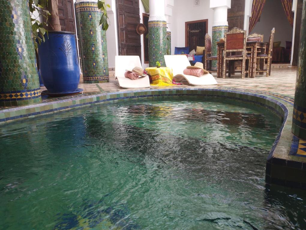 a person laying in chairs next to a pool of water at Riad Tahar Oasis in Marrakesh