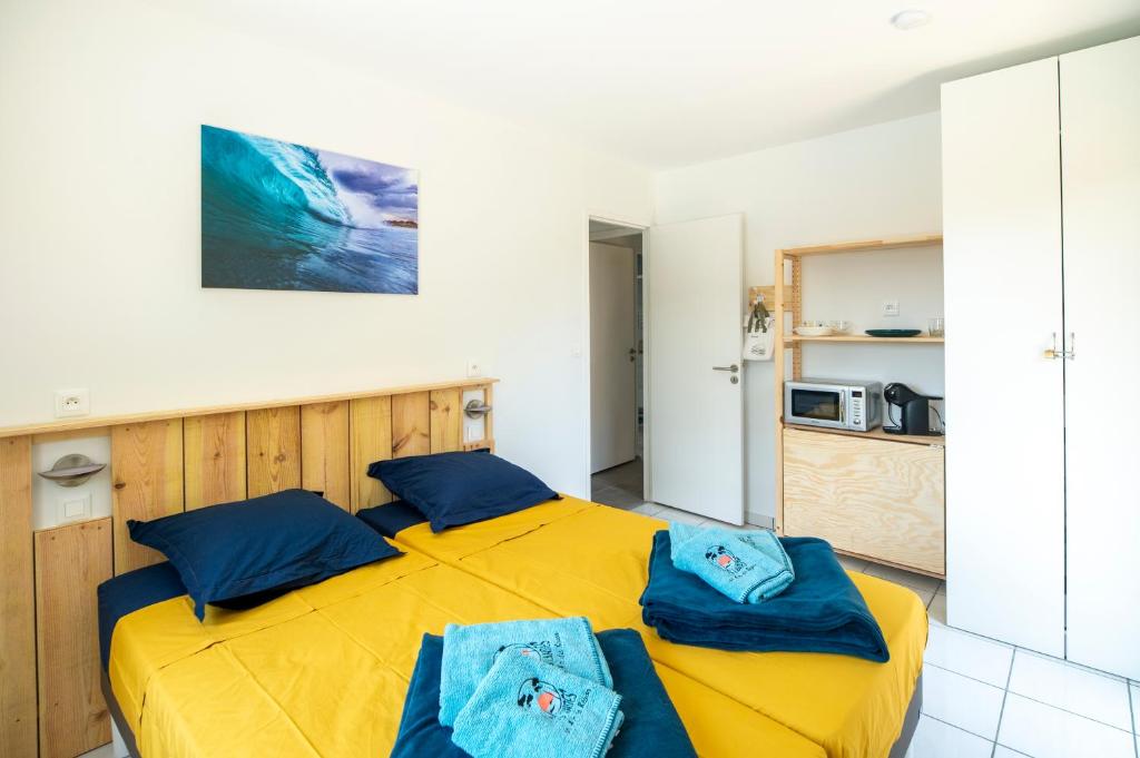 1 dormitorio con cama amarilla y almohadas azules en un Air de Repos, en Vieux-Boucau-les-Bains