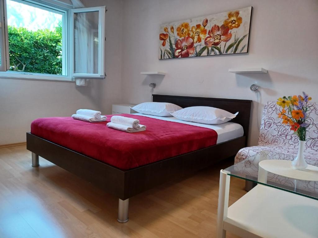 een slaapkamer met een bed met rode lakens en een raam bij MG Ravlic Apartments in Makarska