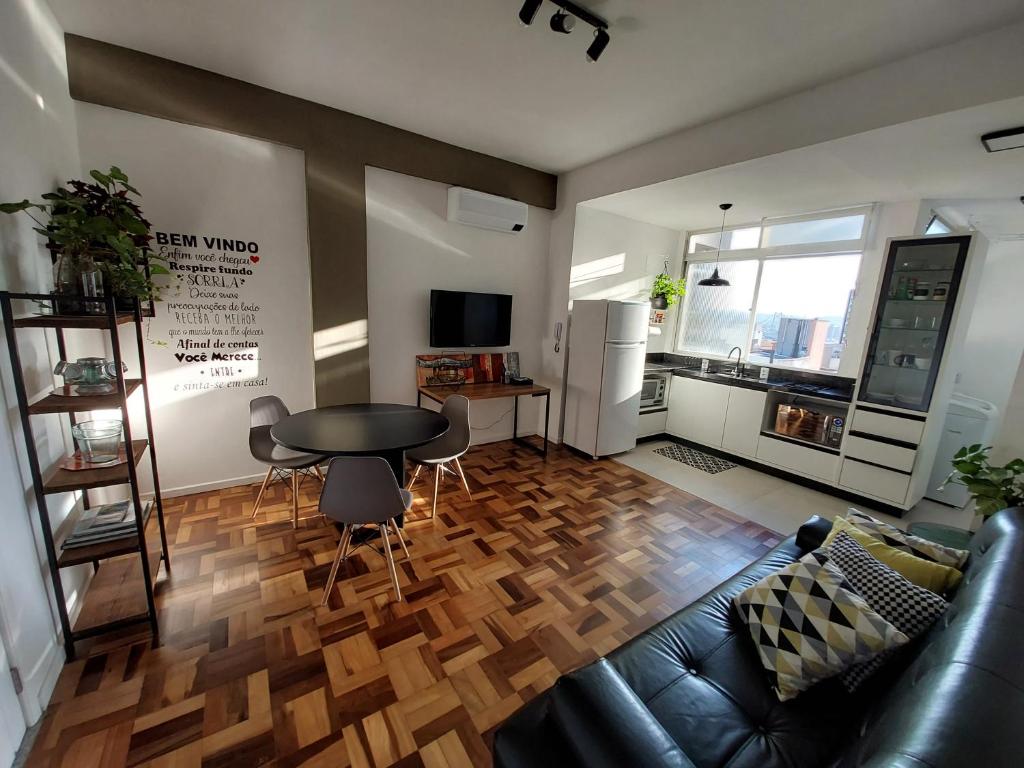 a living room with a black leather couch and a table at Próximo dos melhores hotéis do centro, 2 quartos, portaria 24h in Florianópolis