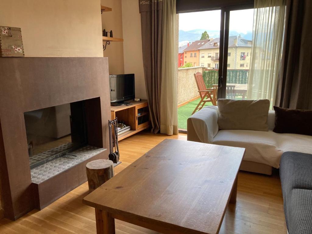 sala de estar con chimenea, sofá y mesa en Cal Mercadé en Puigcerdá