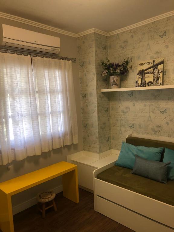 1 dormitorio con cama, ventana y banco en Apartamento aconchegate no centro de Gramado., en Gramado
