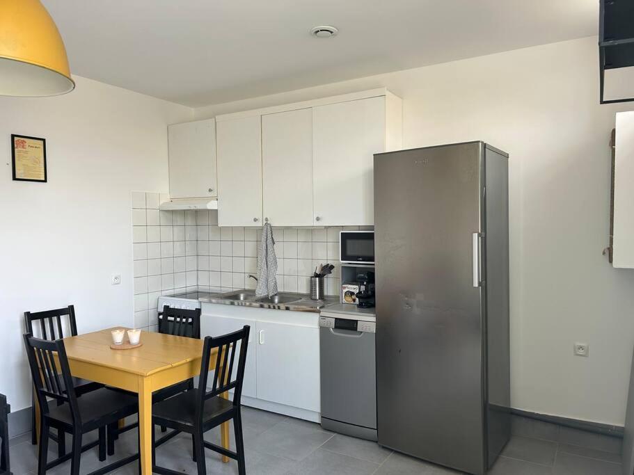 a kitchen with a table and a stainless steel refrigerator at T2 maison entre calme & ville in La Riche