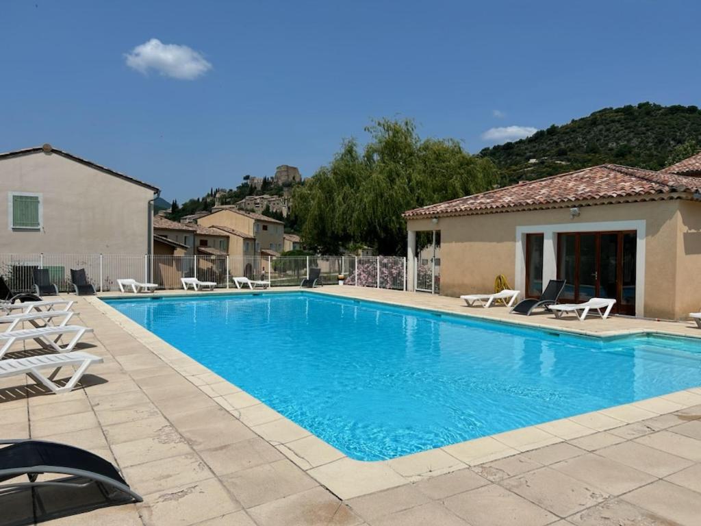 a swimming pool with chairs and a house at Olydea Montbrun-les-Bains in Montbrun-les-Bains