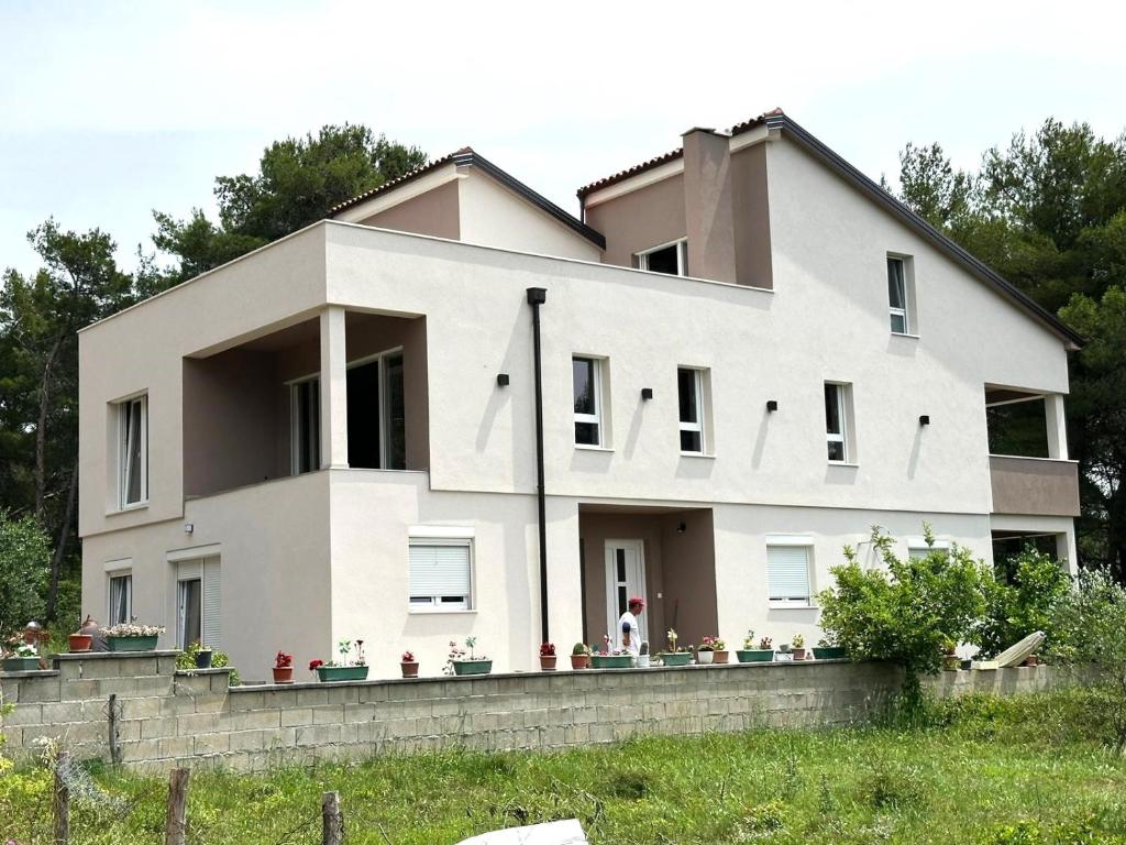 ein großes weißes Haus an einer Steinmauer in der Unterkunft Apartment Lili in Biograd na Moru