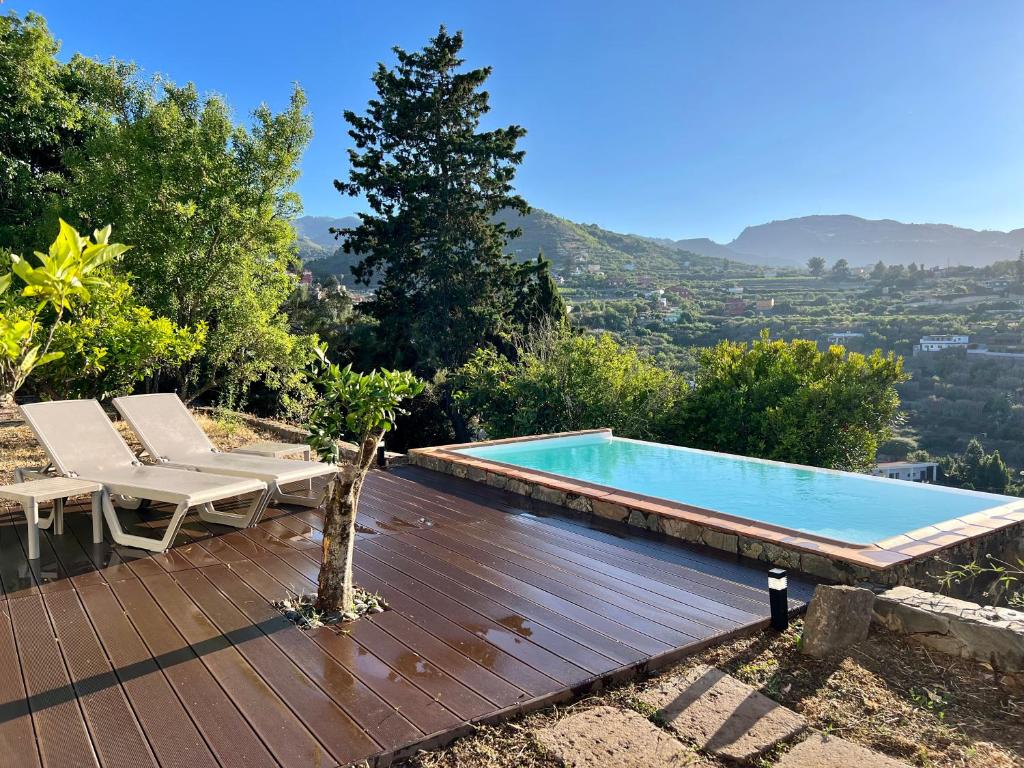 uma piscina num deque de madeira com duas cadeiras ao lado em Casa La Veguetilla en San Mateo em Vega de San Mateo