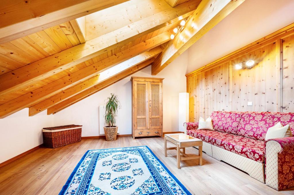 a living room with a red couch and wooden ceilings at Mitterbruggehof Apt Berganemone in Anterselva di Mezzo