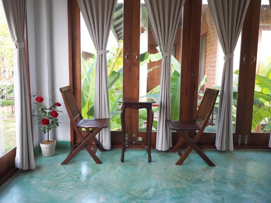 two chairs and a table in a room with windows at BaanSuk Sukhothai Resort in Sukhothai