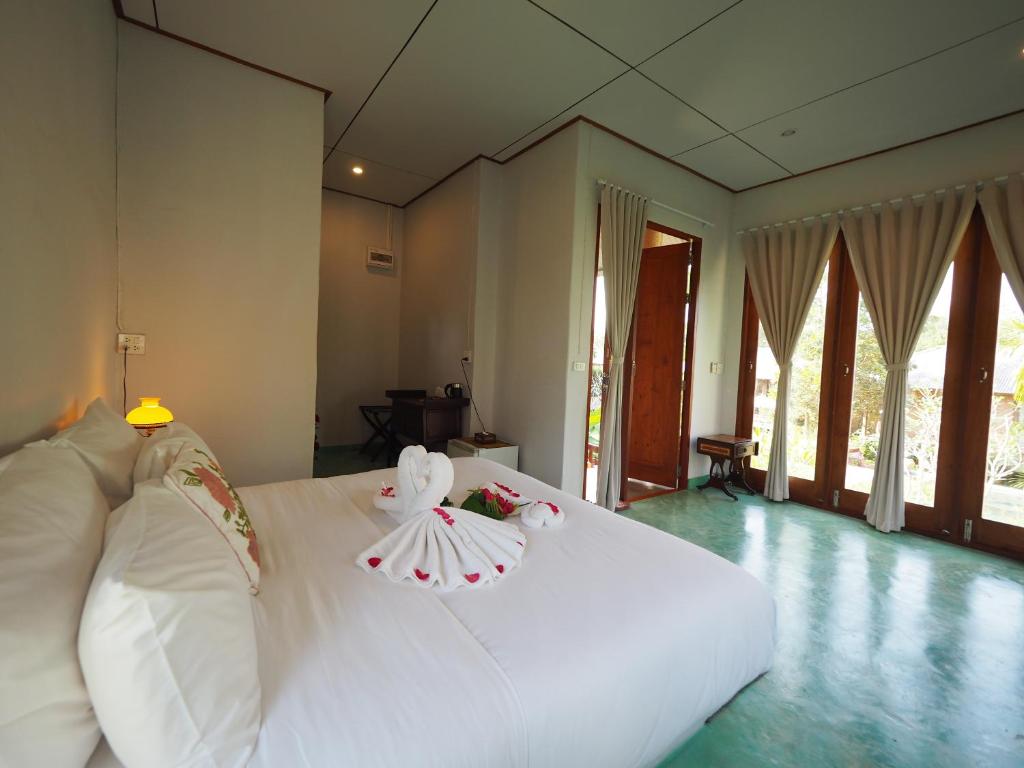 a bedroom with a white bed with towels on it at BaanSuk Sukhothai Resort in Sukhothai