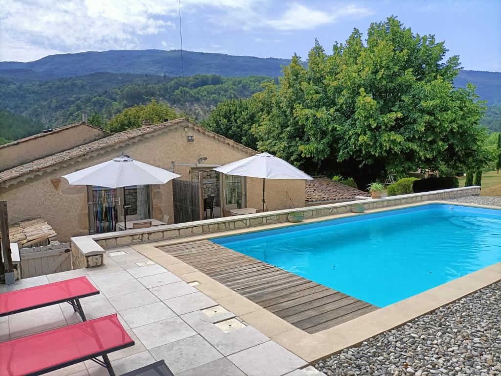 una piscina con 2 sombrillas y una casa en GITE DES ANGES, en Barret-sur-Meouge