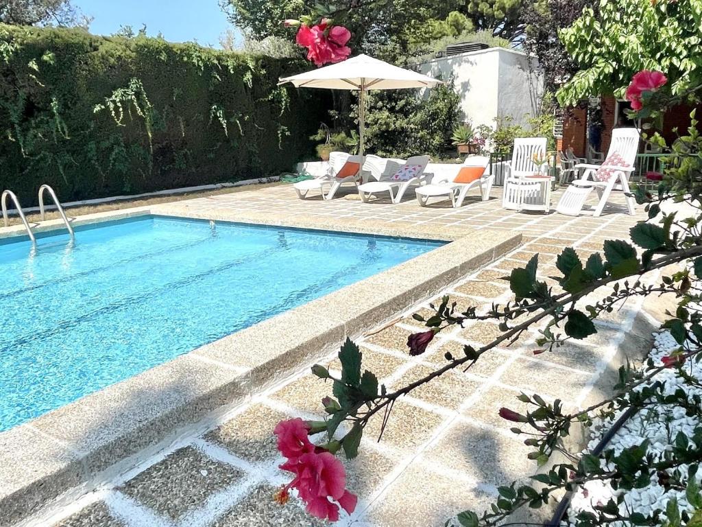 a swimming pool with chairs and an umbrella in a yard at APARTBEACH MAS AIGUESVERDS CLIMATIZADO y PISCINA in Reus