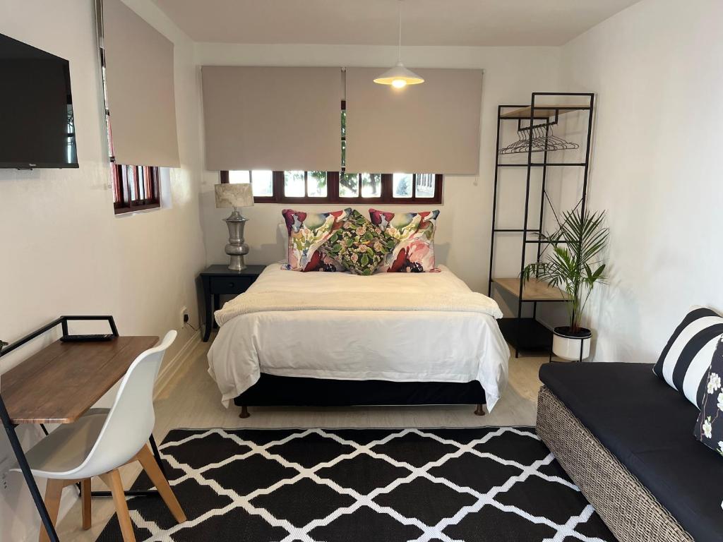 a bedroom with a bed and a table and a couch at The Green Room on Leo Epstein in Johannesburg