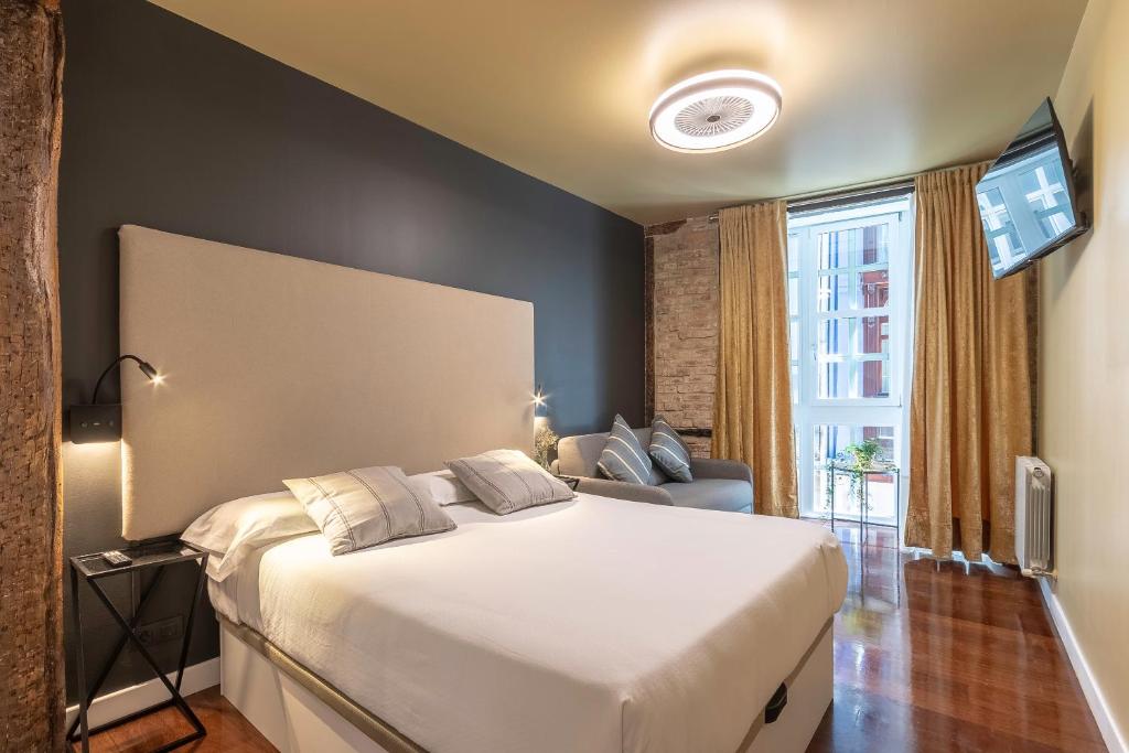 una camera da letto con un grande letto bianco e una finestra di Victorooms a Bilbao