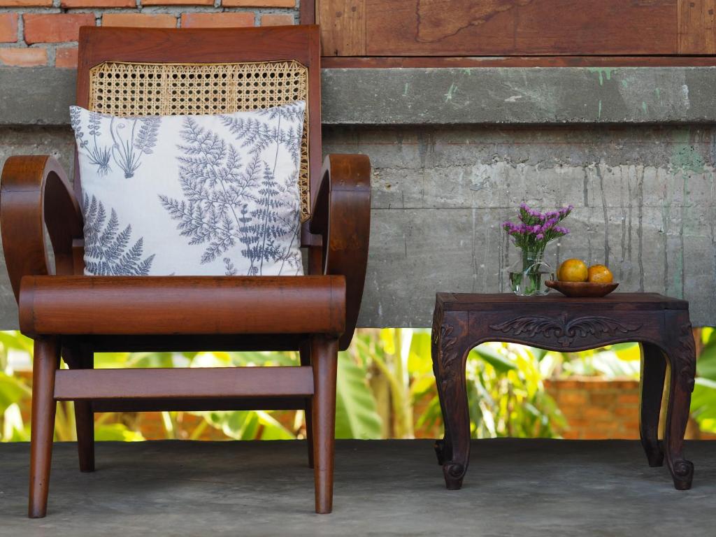 a chair with a pillow and a table with a bowl of fruit at BaanSuk Sukhothai Resort in Sukhothai