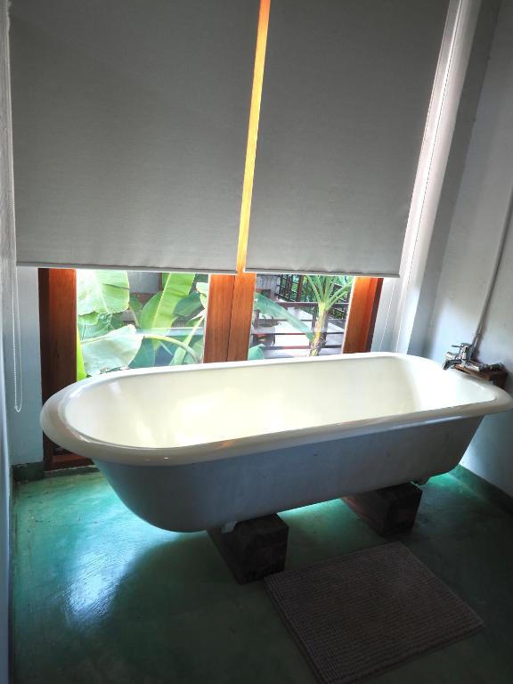 a white bath tub in a room with a window at BaanSuk Sukhothai Resort in Sukhothai