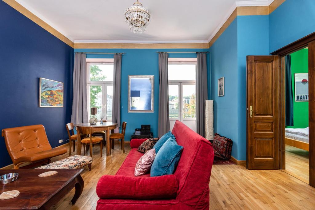 uma sala de estar com paredes azuis e um sofá vermelho em Les Couleurs By Upstairs na Cracóvia