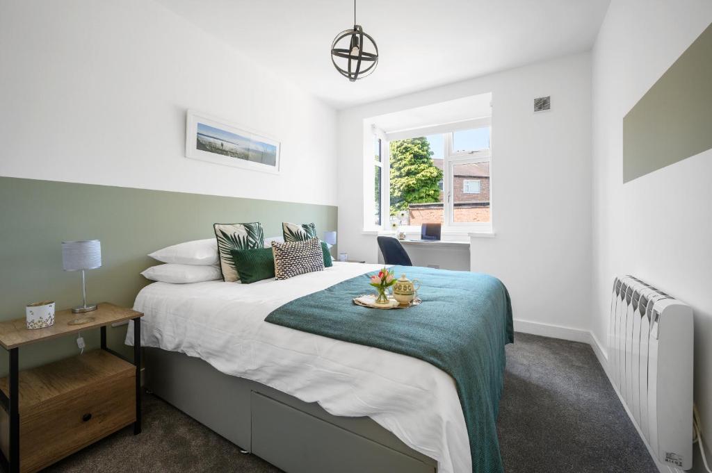 a bedroom with a bed with a green blanket at Ideal Lodgings In Urmston in Urmston