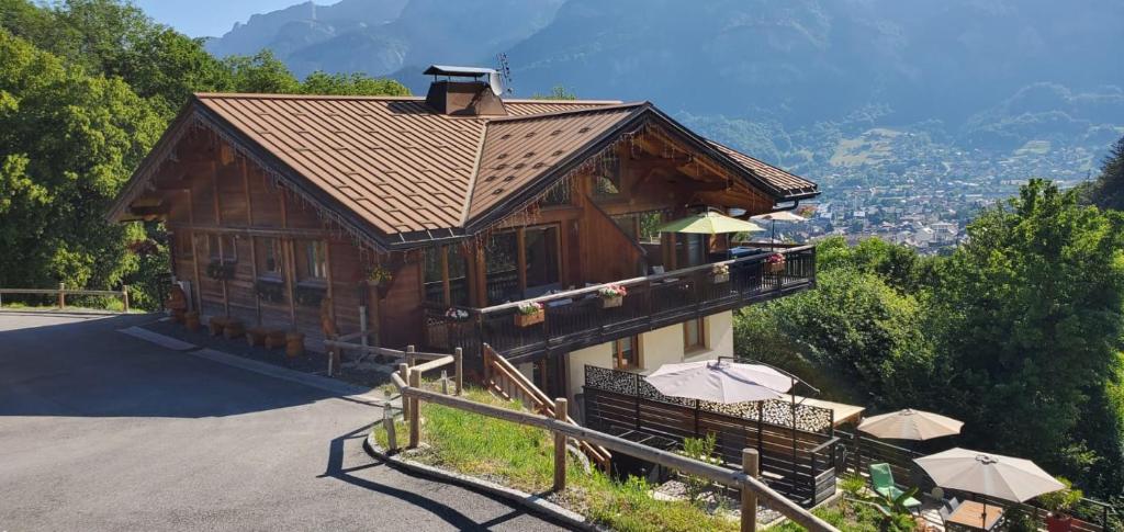 a wooden house with umbrellas in front of it at SUPERBE DEMI CHALET LUXUEUX 120M² 8 Personnes à SALLANCHES. in Sallanches