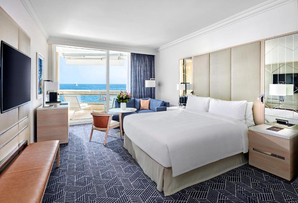 a hotel room with a large bed and a living room at Fairmont Monte Carlo in Monte Carlo