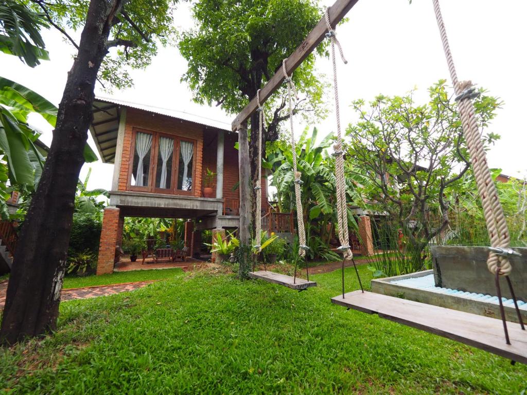 a house with a swing in the yard at BaanSuk Sukhothai Resort in Sukhothai
