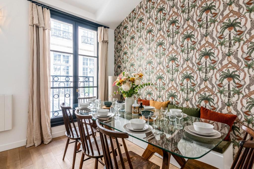 a dining room with a table and chairs and a wallpaper with palm trees at Wonderful flat in the Marais neighbourhood - Paris - Welk in Paris