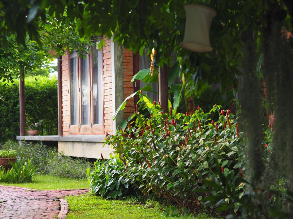 a bush with red flowers in front of a house at BaanSuk Sukhothai Resort in Sukhothai