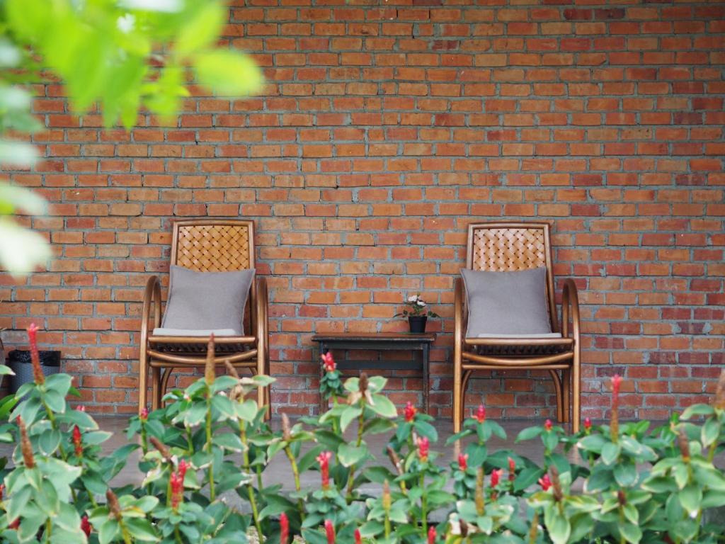 two chairs sitting in front of a brick wall at BaanSuk Sukhothai Resort in Sukhothai