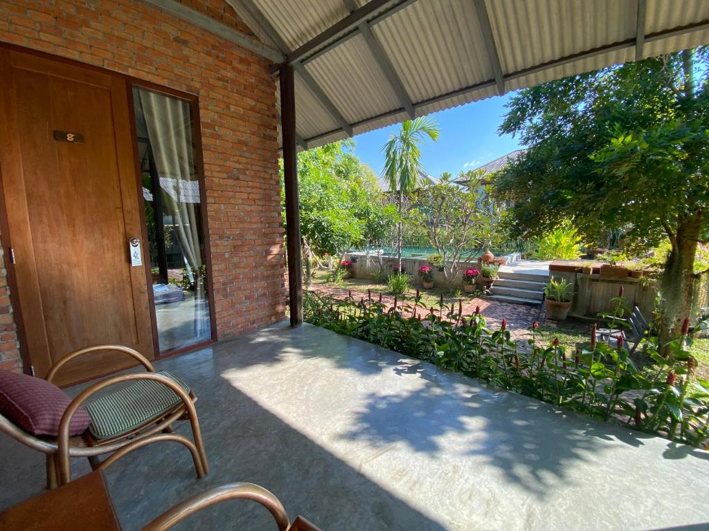 a patio with chairs and a door to a yard at BaanSuk Sukhothai Resort in Sukhothai