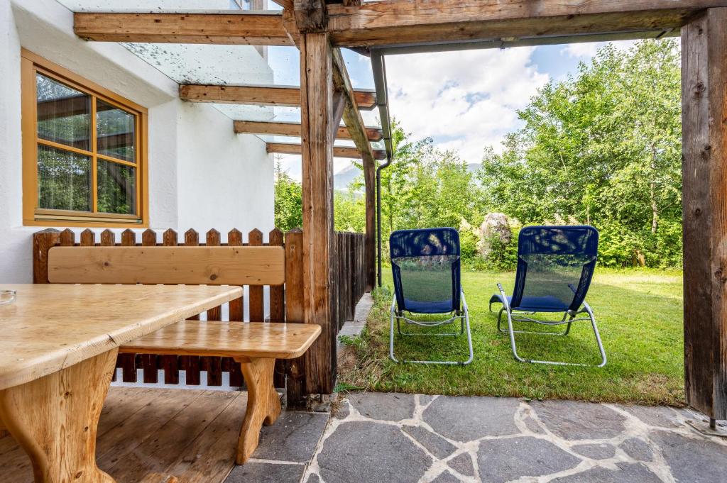 eine Terrasse mit 2 Stühlen und einem Holztisch in der Unterkunft Lindenhof Apt 8 in Vintl