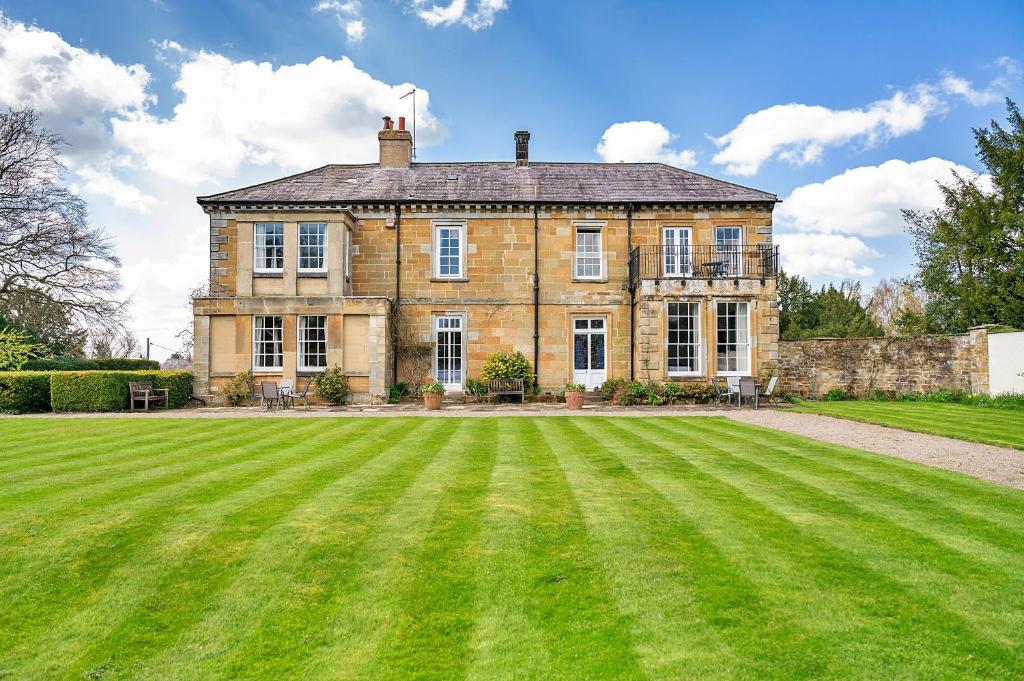 an old brick house with a large grass field at Finest Retreats - Roulston Hall Apt in Thirsk
