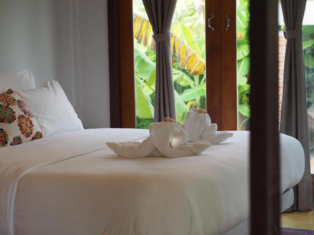 a white towel sitting on a bed with a window at BaanSuk Sukhothai Resort in Sukhothai
