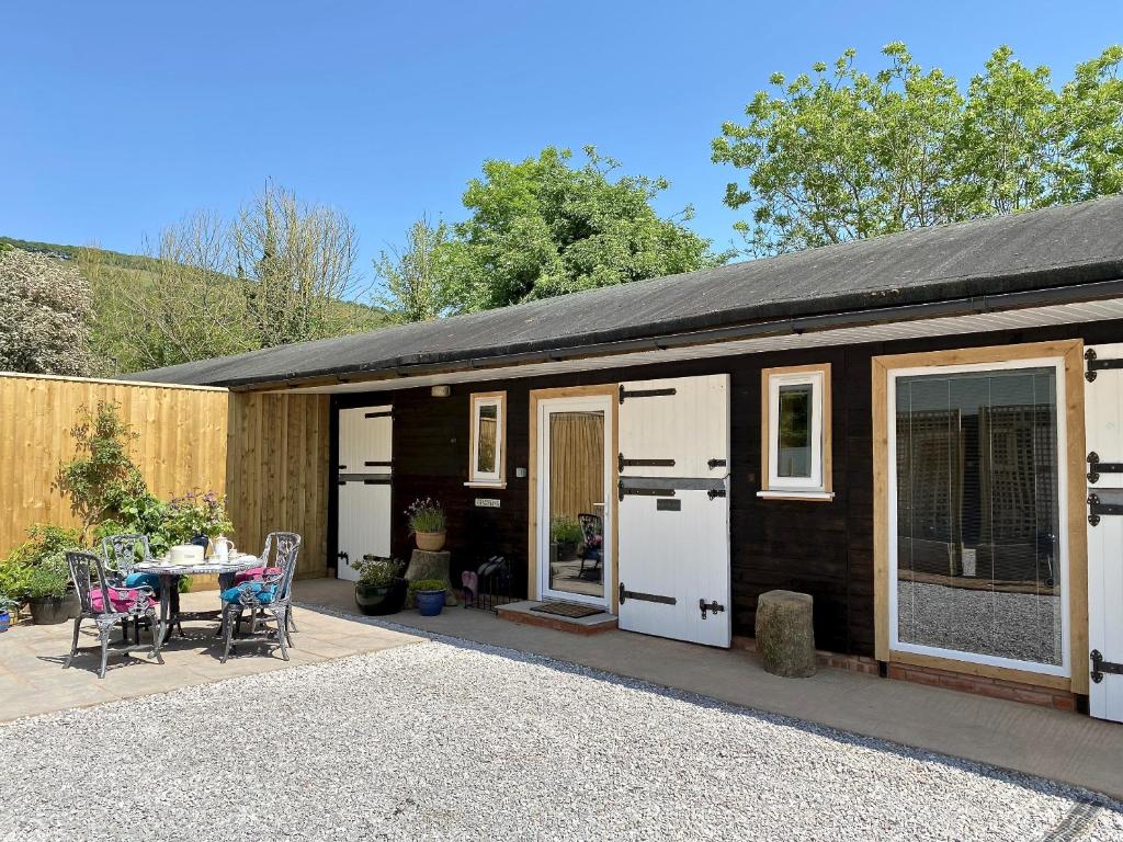 een klein huis met een patio en een tafel bij TVF Stable Suites in Nether Stowey