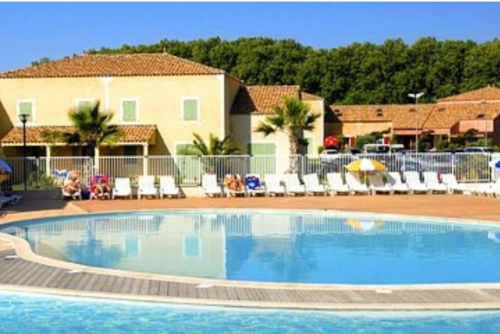 een zwembad in een resort met stoelen bij Maison chaleureuse F3 avec 3piscines dans résidence in Béziers