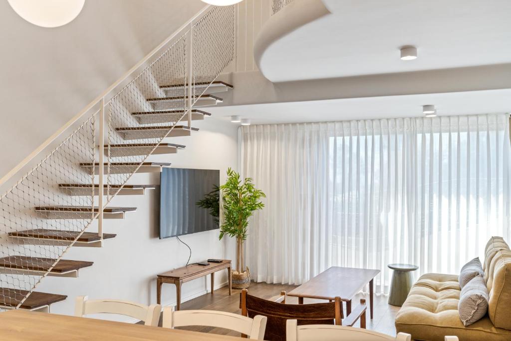a staircase in a living room with a table and chairs at Gaudi Beach view in Tel Aviv