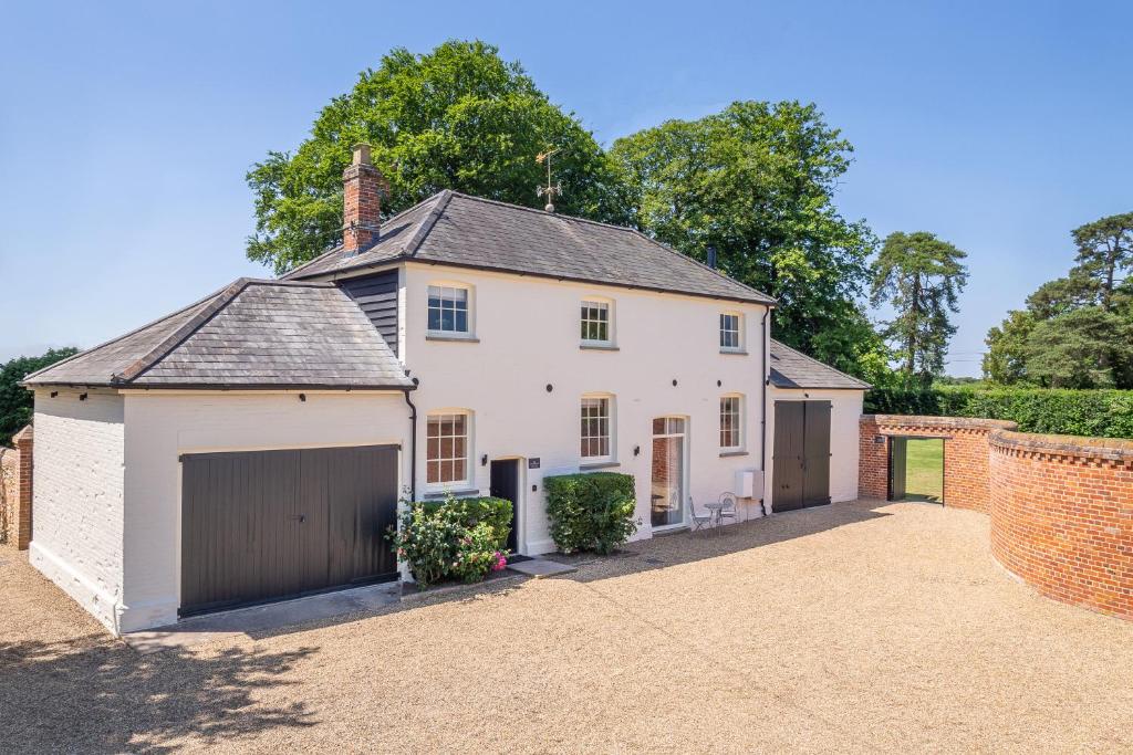 a large white house with a garage at Crisply stylish Georgian cottage - Orchard Coach House in Sudbury