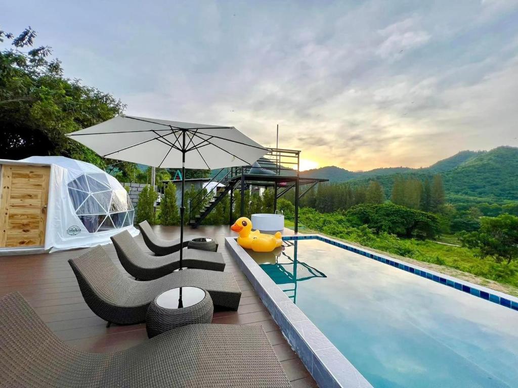 a pool with chairs and an umbrella next to a swimming pool at เคียงดาว โฮมสเตย์ แก่งกระจาน in Ban Song Phi Nong