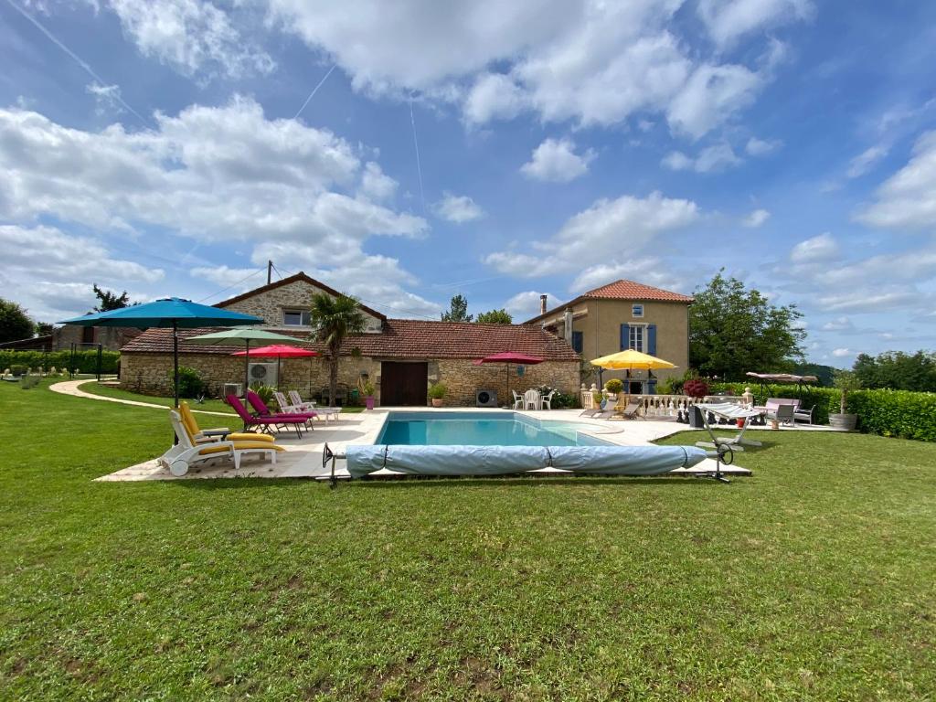 - une piscine dans une cour avec des chaises et des parasols dans l'établissement Entre ciel et Lot, à Prayssac