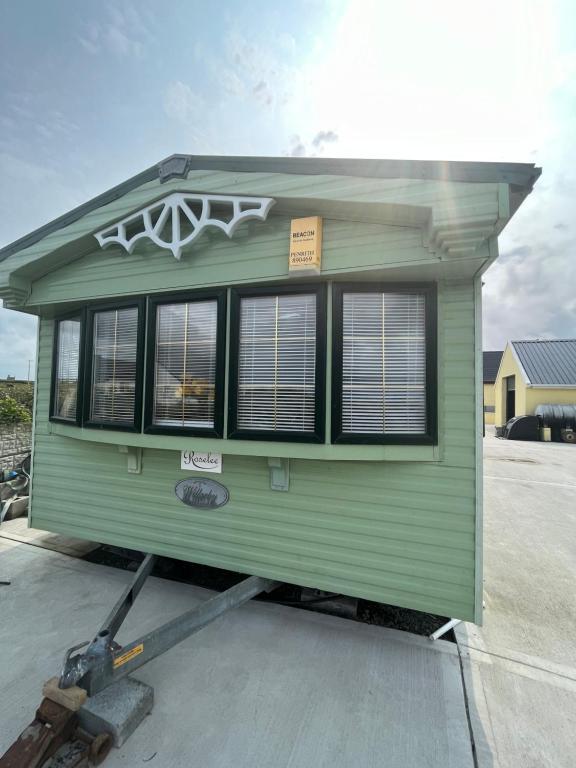 una casita verde que se está construyendo en una entrada en Seaside Chalet en Quilty