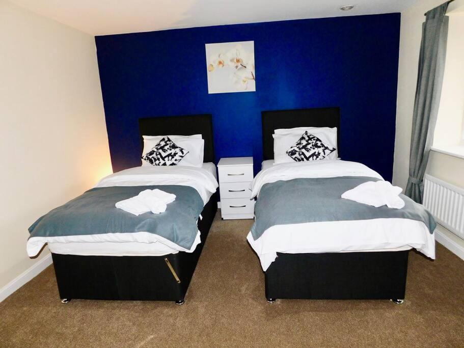 曼徹斯特的住宿－AMILA House Manchester, Modern, Spacious, Sleeps 7 With Parking，卧室设有两张床铺,拥有蓝色的墙壁
