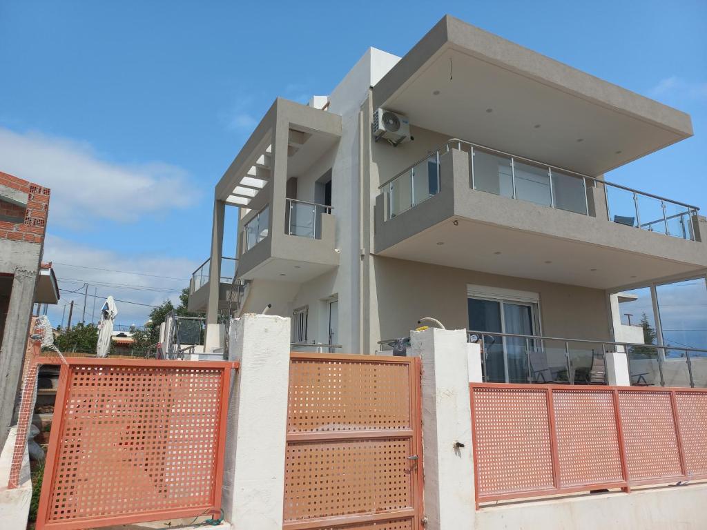 ein Haus mit einem orangenen Tor davor in der Unterkunft Airport View Apartments in Artemida