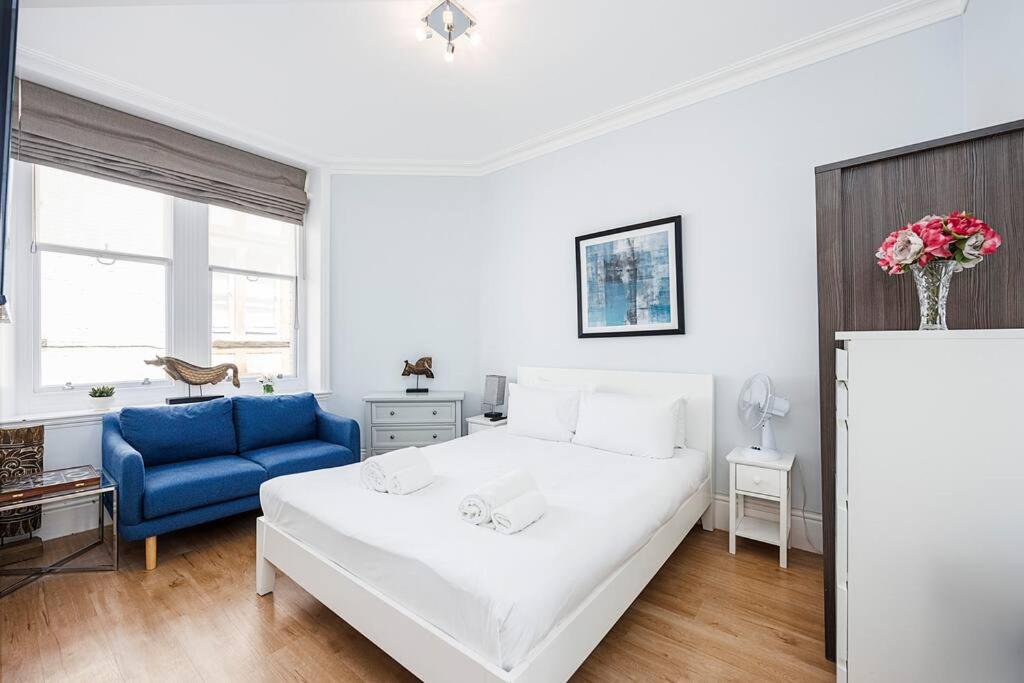 a bedroom with a white bed and a blue couch at Charing Cross Road One Bedroom in London