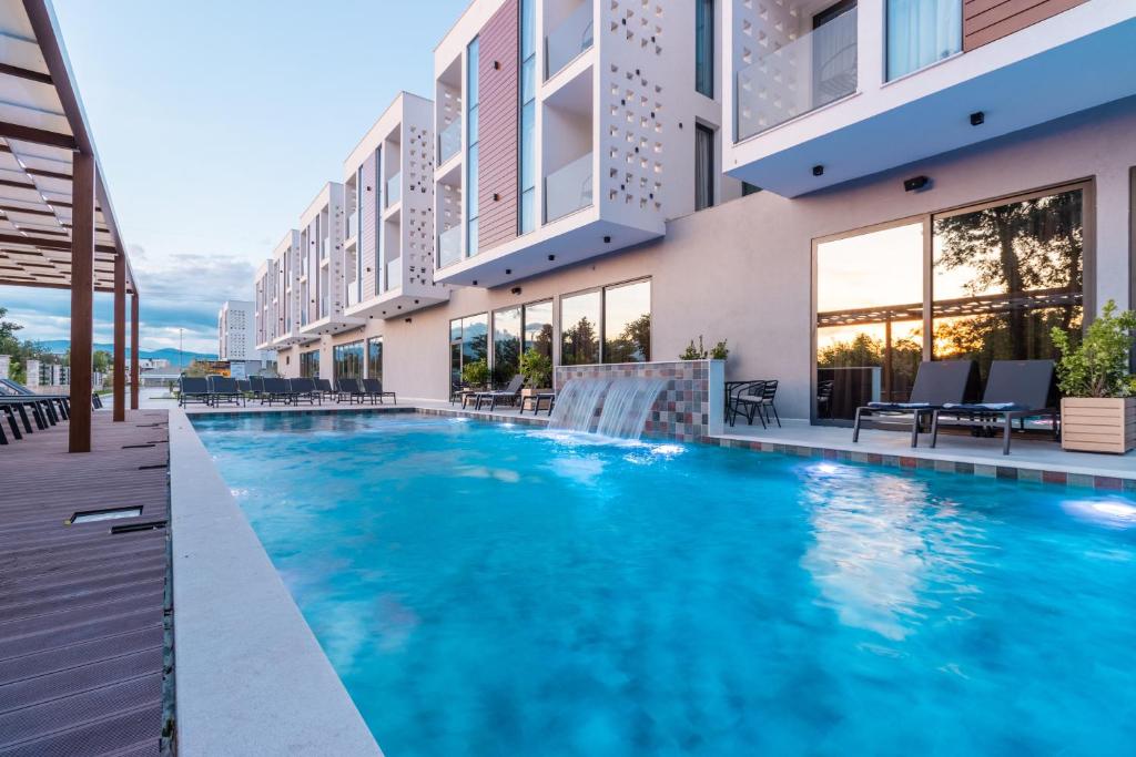 a swimming pool in front of a building at Trio Resort in Ulcinj