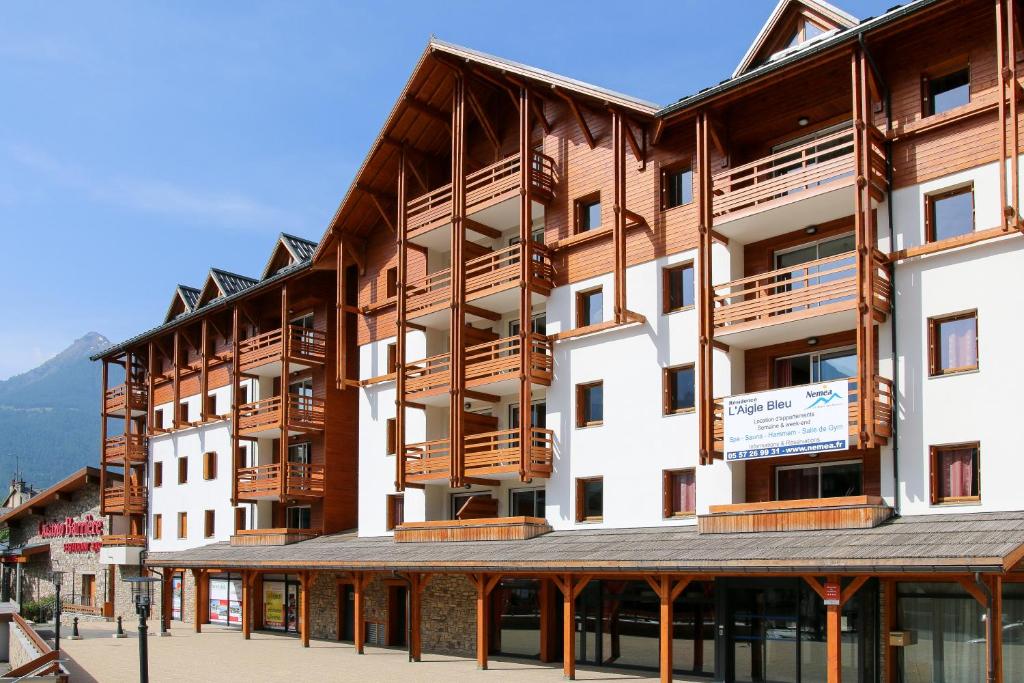 um grande edifício com varandas de madeira numa rua em Résidence Néméa L'Aigle Bleu em Briançon