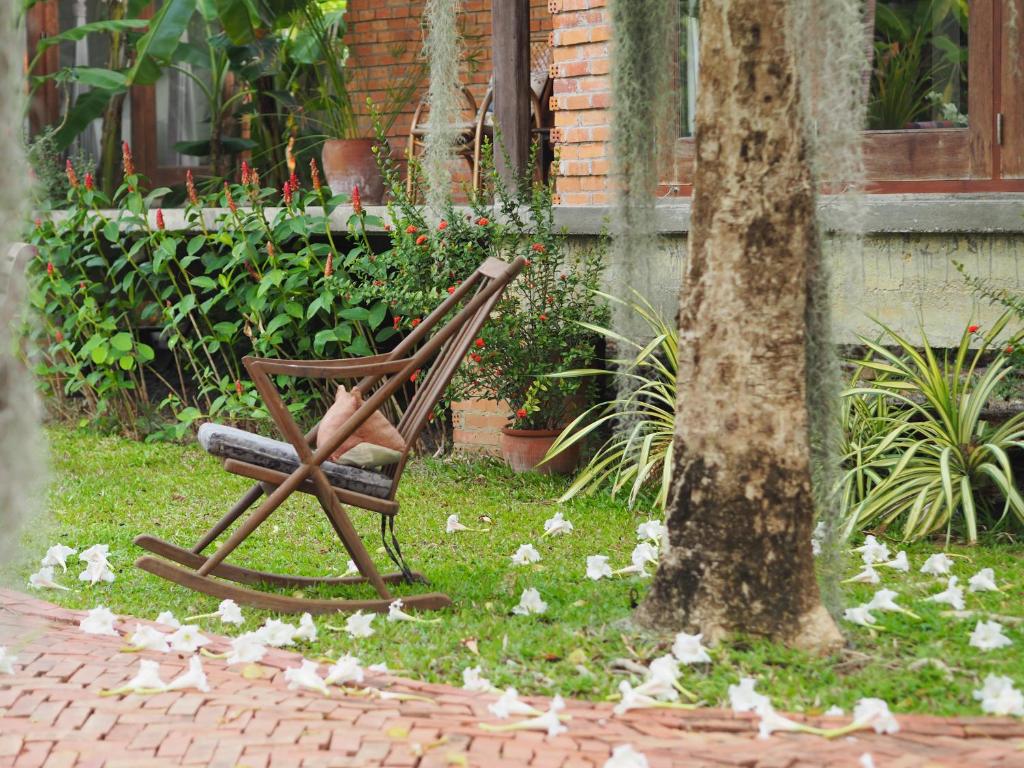 a wooden chair sitting next to a tree at BaanSuk Sukhothai Resort in Sukhothai