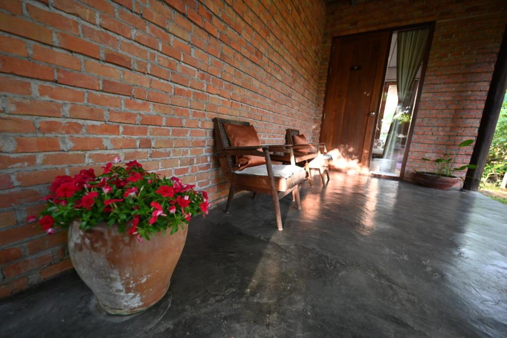 a patio with a brick wall and a chair and flowers at BaanSuk Sukhothai Resort in Sukhothai