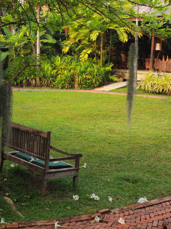 a wooden bench sitting in a field of grass at BaanSuk Sukhothai Resort in Sukhothai