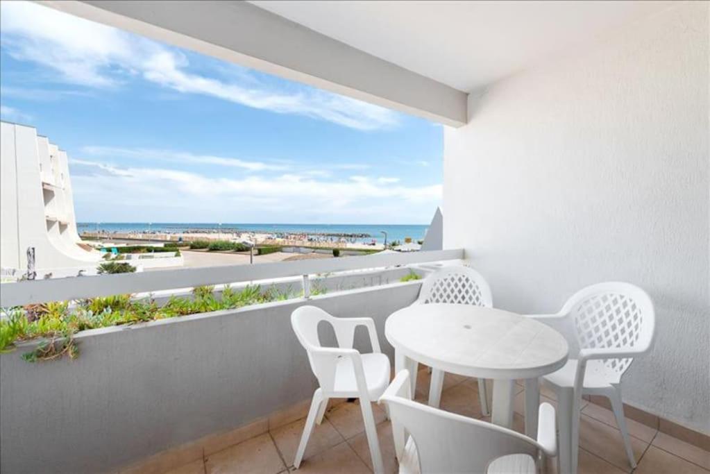 d'un balcon avec une table et des chaises blanches donnant sur l'océan. dans l'établissement Joli Studio Cabine 1ère ligne avec parking privé, à Palavas-les-Flots