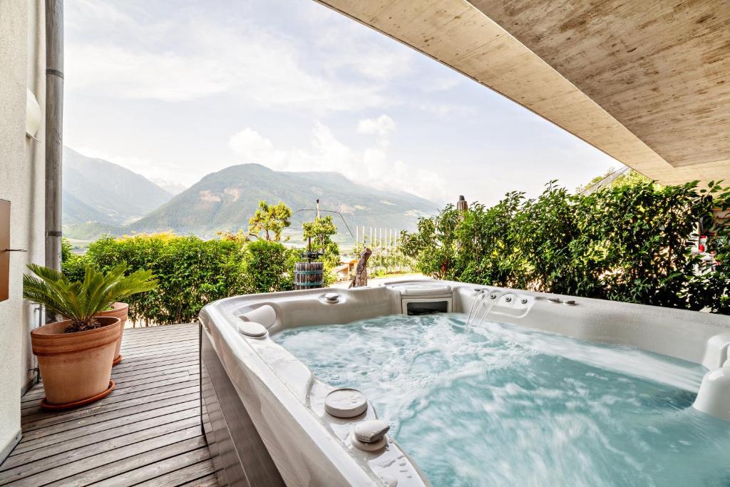 una bañera de hidromasaje en una terraza con montañas al fondo en Langstein Wohnung Sonnenblume, en Coldrano
